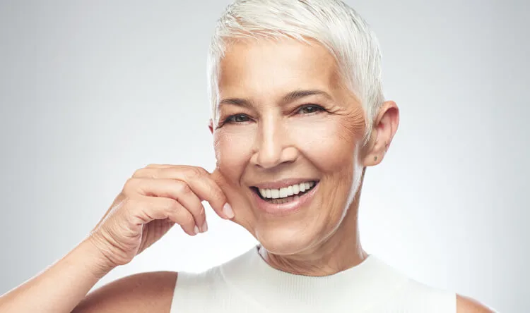 A radiant older woman with smooth skin smiling, symbolizing confidence and the benefits of supplements for skin and beauty.