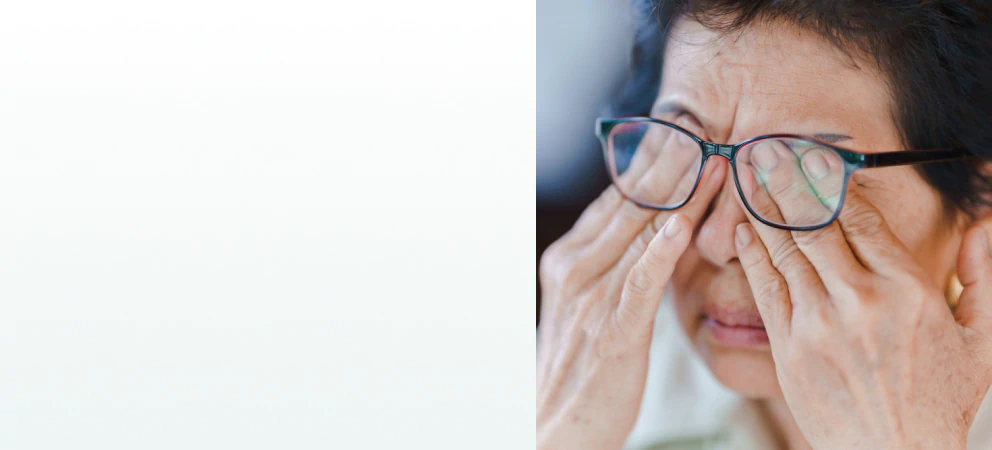 An elderly woman rubbing her eyes while wearing glasses, representing the need for supplements for vision support.