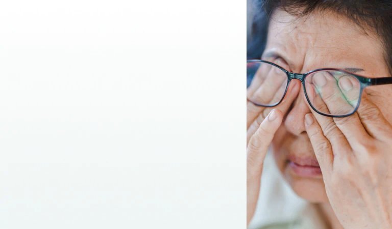 An elderly woman rubbing her eyes while wearing glasses, representing the need for supplements for vision support.