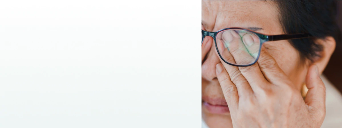 An elderly woman rubbing her eyes while wearing glasses, representing the need for supplements for vision support.